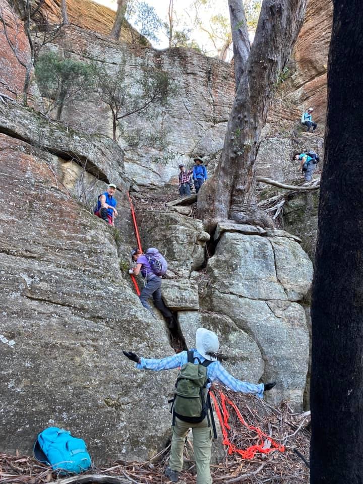 People climbing up large rock face